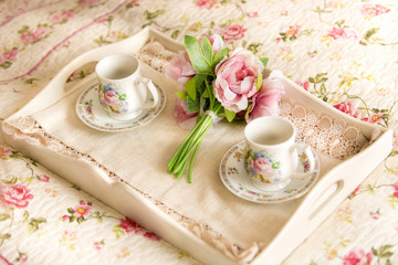 vintage tray with flowers and teacups lying on bed