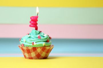 Delicious birthday cupcake on table on bright background