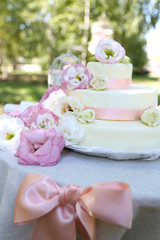 Beautiful wedding cake with flowers on table, outdoors