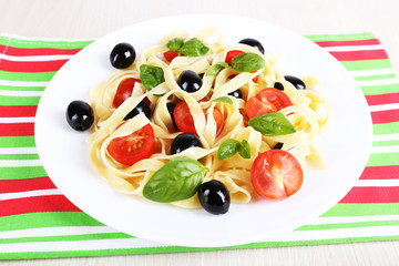 Spaghetti with tomatoes, olives and basil leaves