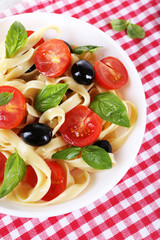 Spaghetti with tomatoes, olives and basil leaves