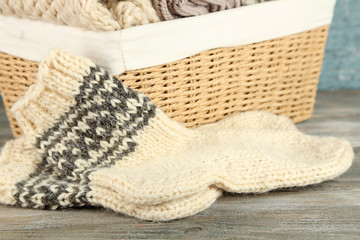 Knitting yarn in basket and socks, on wooden background