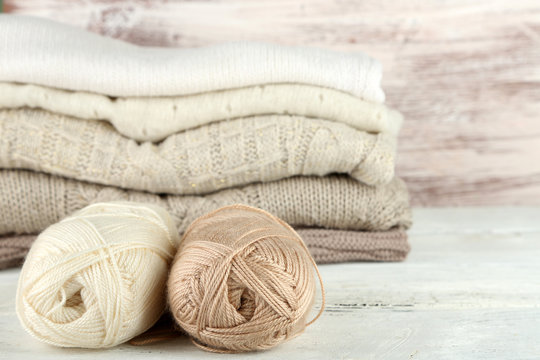 Knitting clothes and yarn on wooden background