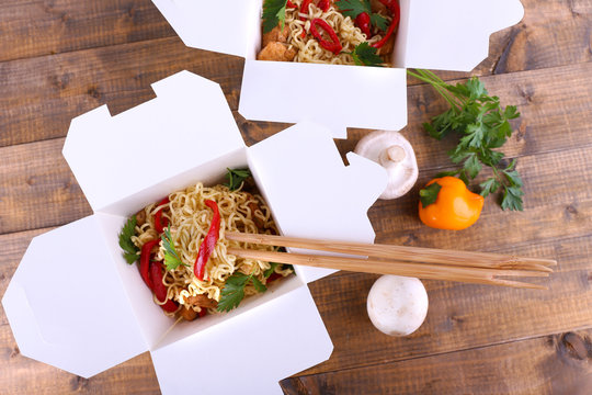 Chinese noodles in takeaway boxes with mushrooms and parsley