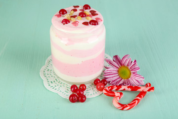 Cranberry milk dessert in glass jar, on color wooden background