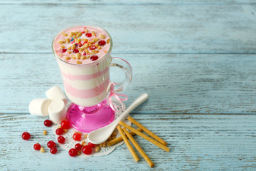 Cranberry milk dessert in glass, on color wooden background