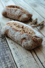 Bread rolls with wheat ears on wooden table