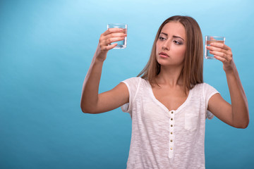 Portrait of a pretty girl holding two glasses with clean water i