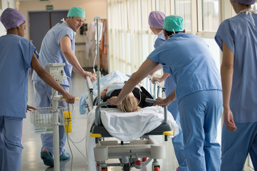 Medical professionals pushing patient on gurney in a hospital