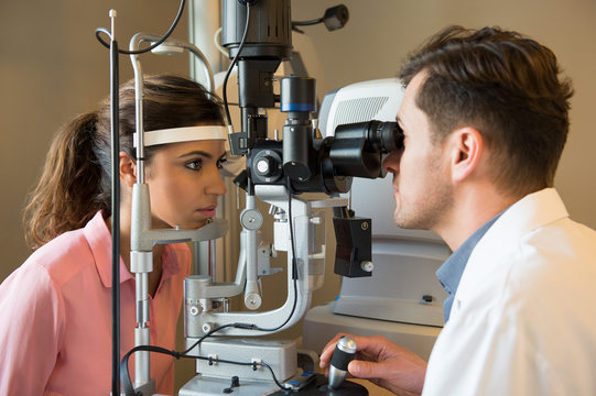 Male optometrist examining woman's eyes