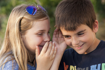 boy and girl counting a secret to the ear