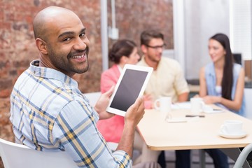 Businessman using her digital tablet smiling at camera