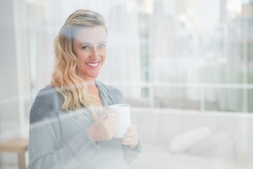 Smiling pretty blonde holding coffee