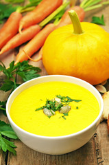 Pumpkin soup and fresh vegetables on wooden table