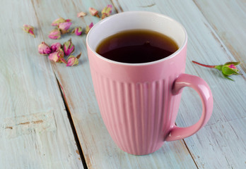 Cup of  tea with roses on a  blue wooden table