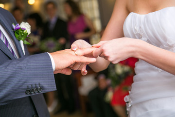 Obraz na płótnie Canvas bride putting a wedding ring on groom's finger