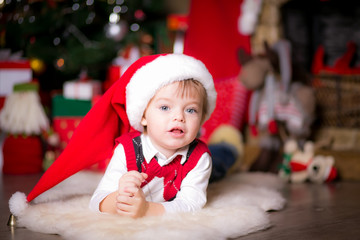 happy little boy near a Christmas tree opening gifts