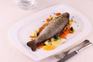 Fried whole trout with vegetables and cutlery