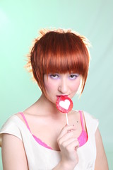 Girl with red hair with a lollipop in a white dress