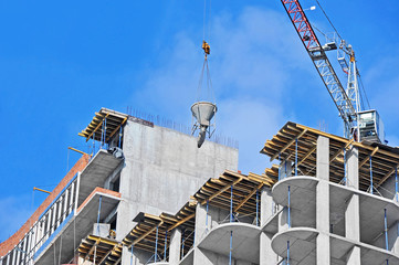 Crane lifting concrete mixer container against blue sky