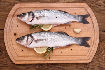 Two fresh moronidae fish on cutting board with ingredients