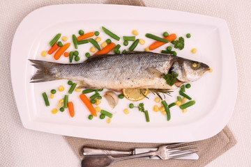 Fried whole sea bass with vegetables and lemon