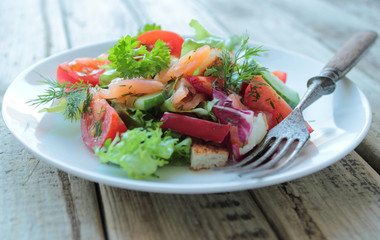 White plate with salad with salmon and fresh vegetables