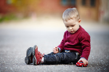 little boy plays with toy car