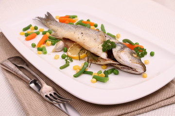 Fried whole sea bass with vegetables, lemon