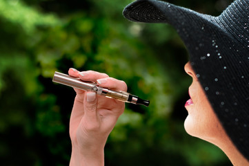 jeune femme avec chapeau avec une cigarette électronique