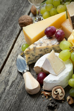 fresh cheeses, grapes and walnuts on a wooden background
