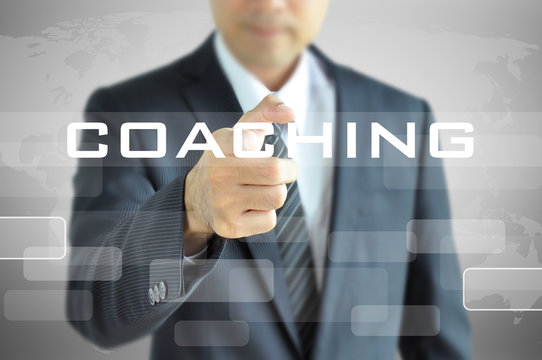 Businessman pointing to COACHING word on virtual screen