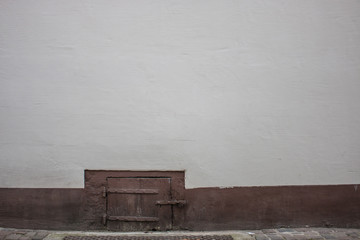 Hintergrund – alte verputzte Mauer mit Kellerfenster