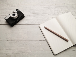 Fototapeta premium Blank textbook and vintage camera on a wooden table
