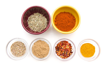 Spices in bowls seen from above on white background