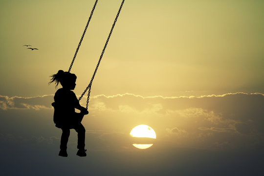 Girl on swing at sunset