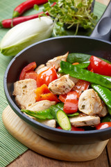 chicken breast meat an vegetables on frying pan