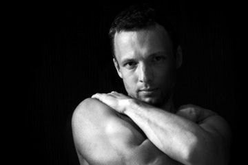 Strong muscular young Caucasian man portrait on black background