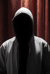 Portrait of Invisible man in the hood with red curtain backgroun