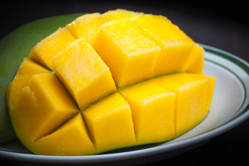 Macro photo of yellow sliced mango on white plate