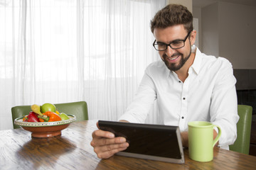 Male drinking coffee and reading the news on his tablet