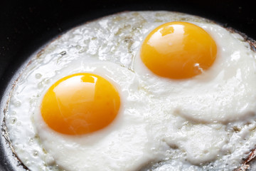 Closeup photo of two scrambled eggs in black frying pan