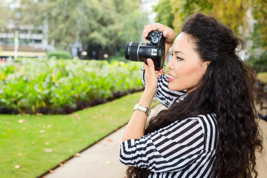 young woman taking photos in the park.