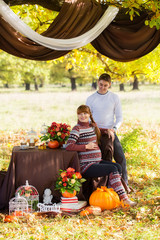 Beautiful Young Pregnant Couple Having Picnic in autumn Park. Ha