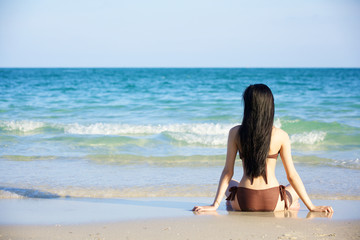 sexy beautiful woman in brown bikini sitting on the beach