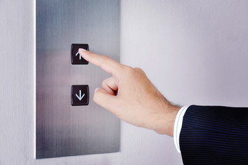 Businessman hand touching going up sign on lift control panel