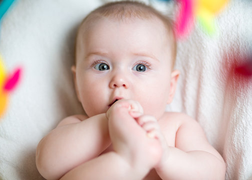 baby girl pulling foot to mouth