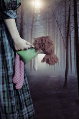 Misty haunted forest and a child in a dress with a doll