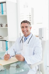 Happy doctor sitting at his desk