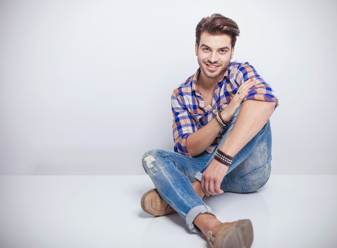 young fashion man sitting on white studio background